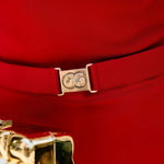 Close-up of a red knit garment with a gold belt and gold buttons.
