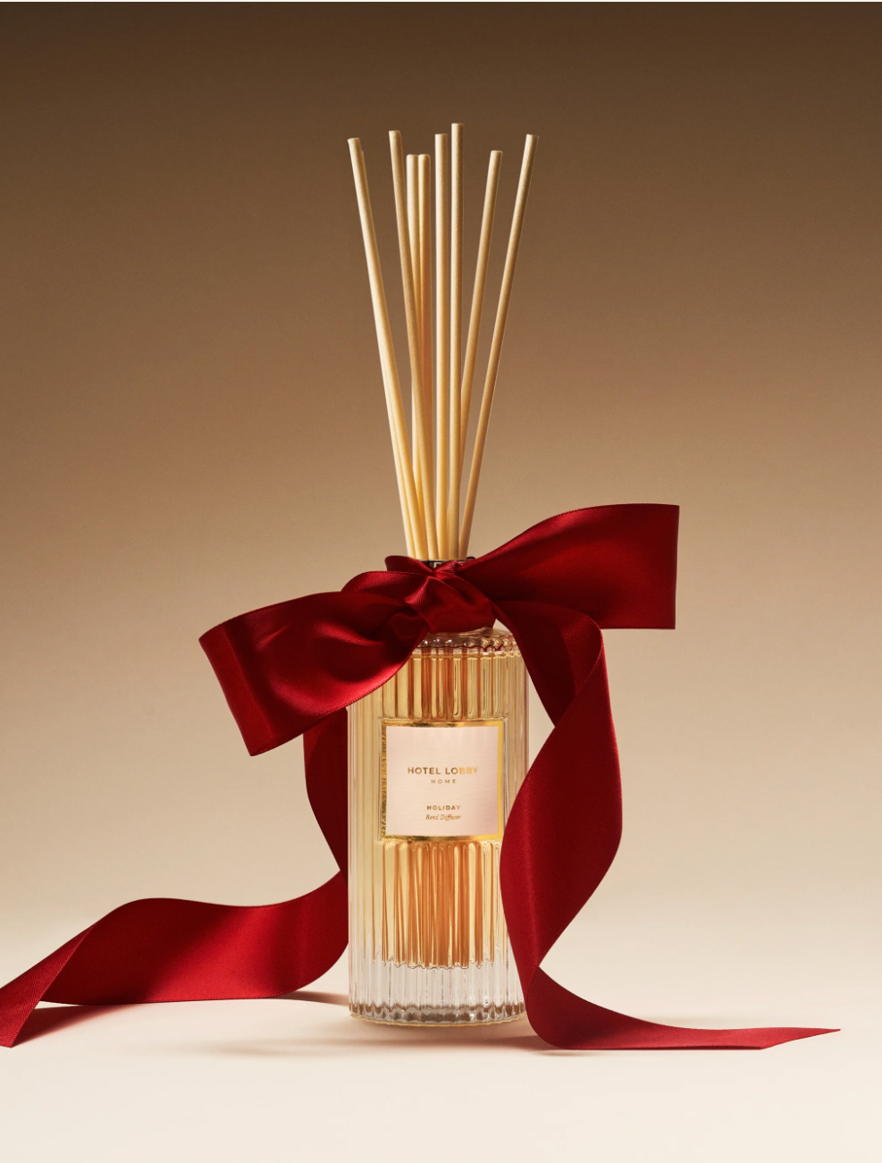 Diffuser with reeds and a red ribbon on a beige background