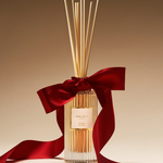 Diffuser with reeds and a red ribbon on a beige background
