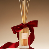 Diffuser with reeds and a red ribbon on a beige background