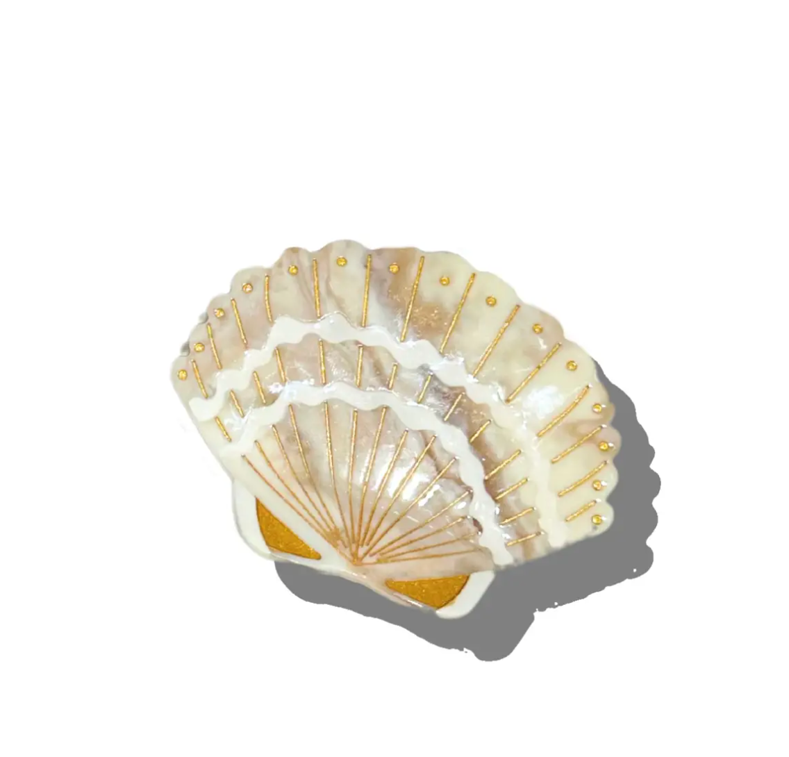Decorative shell hair clip with gold accents on a white background