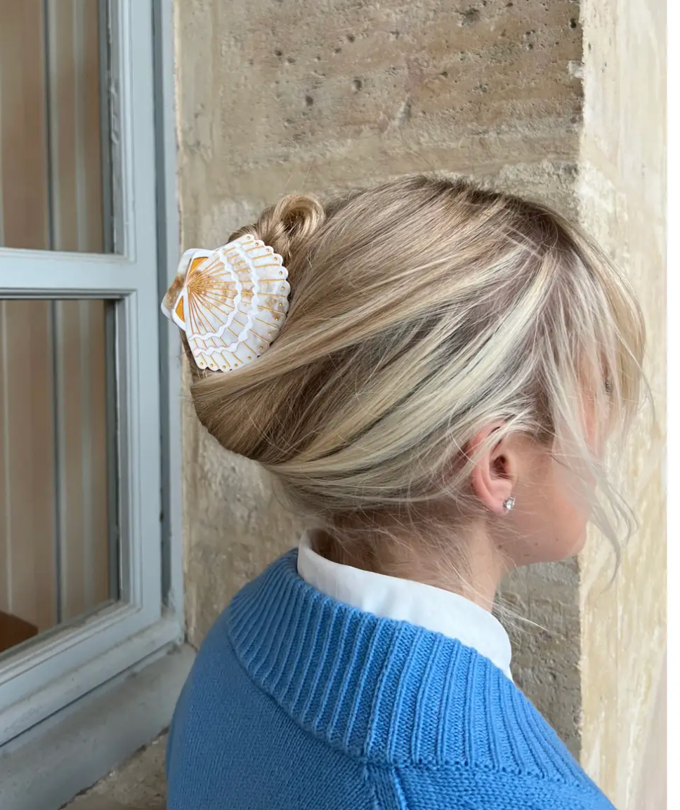 Person wearing a shell hair accessory with a stone wall background
