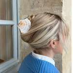 Person wearing a shell hair accessory with a stone wall background