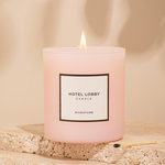 Pink candle labeled 'Hotel Lobby' on a beige stone surface with a soft background