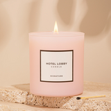 Pink candle labeled 'Hotel Lobby' on a beige stone surface with a soft background