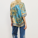 Woman wearing a patterned top and jeans on a white background