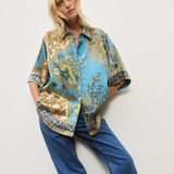 Woman wearing a patterned shirt and jeans on a white background