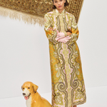 Woman in a patterned dress standing next to a ceramic dog on a white background