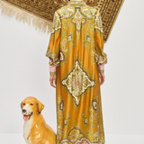 Woman in a patterned dress standing next to a dog statue with a decorative rug in the background
