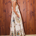 Woman wearing a floral dress standing against a wooden wall.