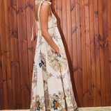 Woman wearing a floral dress standing against a wooden wall.