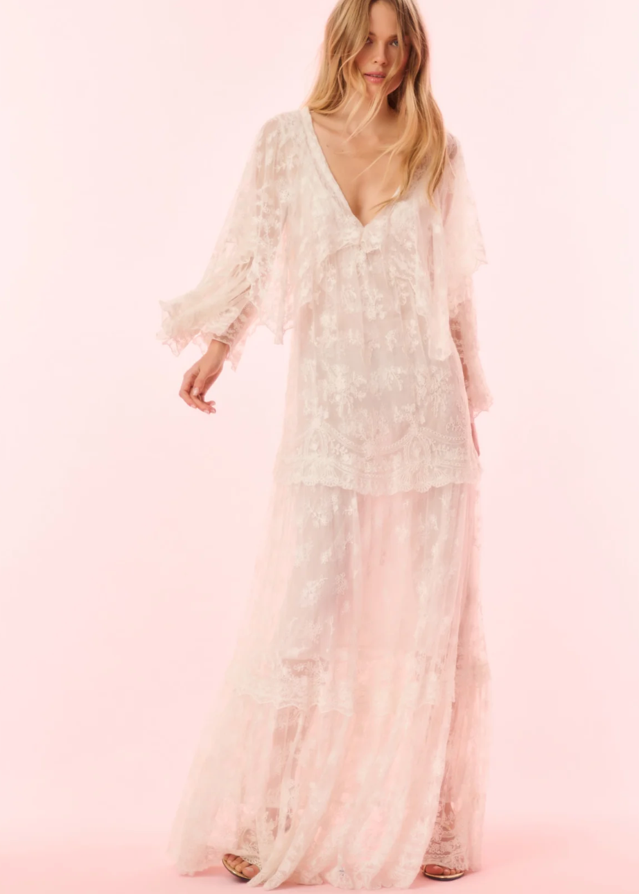 Woman wearing a white lace dress on a pink background