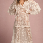 Woman wearing a floral lace dress against a pink background