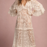 Woman wearing a floral lace dress against a pink background