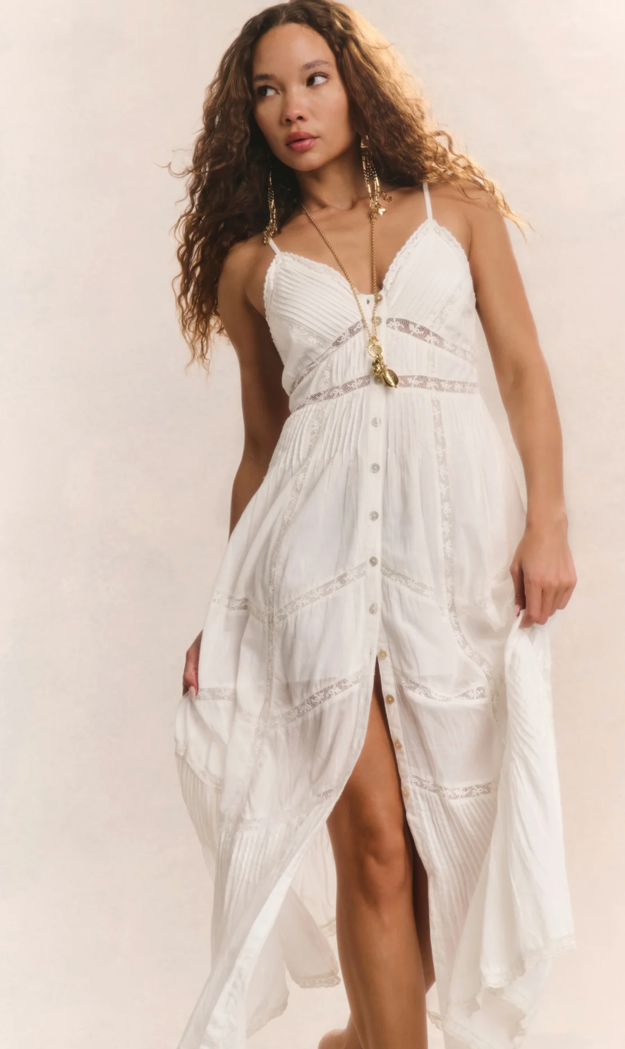 Woman wearing a white dress with gold accents on a plain background