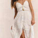 Woman wearing a white dress with gold accents on a plain background