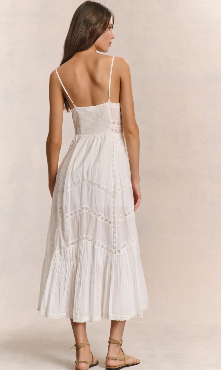 Woman wearing a white dress with thin straps on a plain background