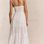Woman wearing a white dress with thin straps on a plain background