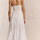 Woman wearing a white dress with thin straps on a plain background