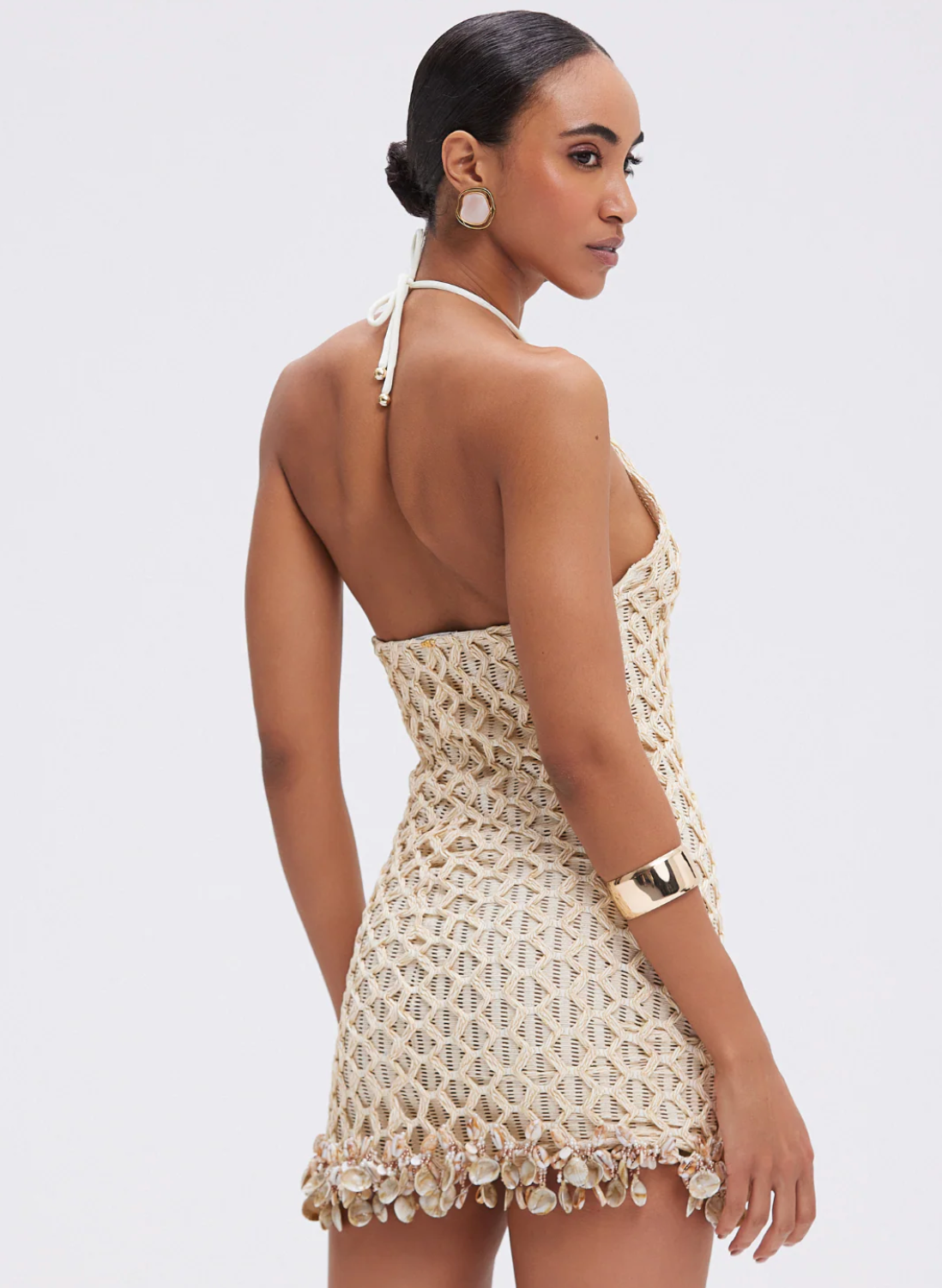 Woman wearing a beige crochet dress on a white background
