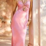 Woman in a pink dress standing outdoors near classical architecture