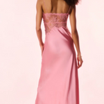 Woman wearing a pink evening gown with lace details on a light pink background
