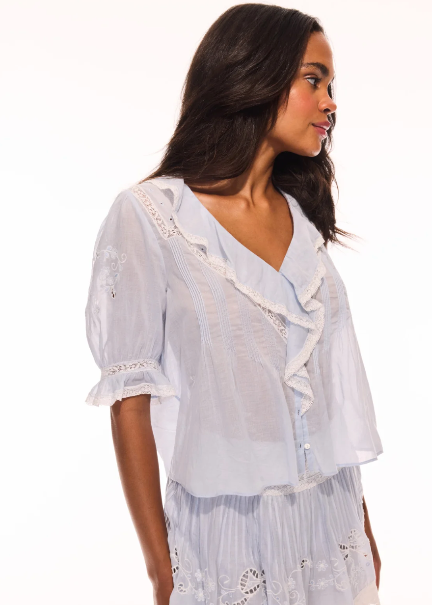 Woman wearing a white embroidered top and skirt on a white background