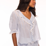 Woman wearing a white embroidered top and skirt on a white background