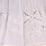 Close-up of a white lace garment with floral embroidery
