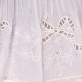 Close-up of a white lace garment with floral embroidery