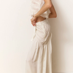 Woman wearing a white lace dress against a plain background