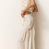 Woman wearing a white lace dress against a plain background