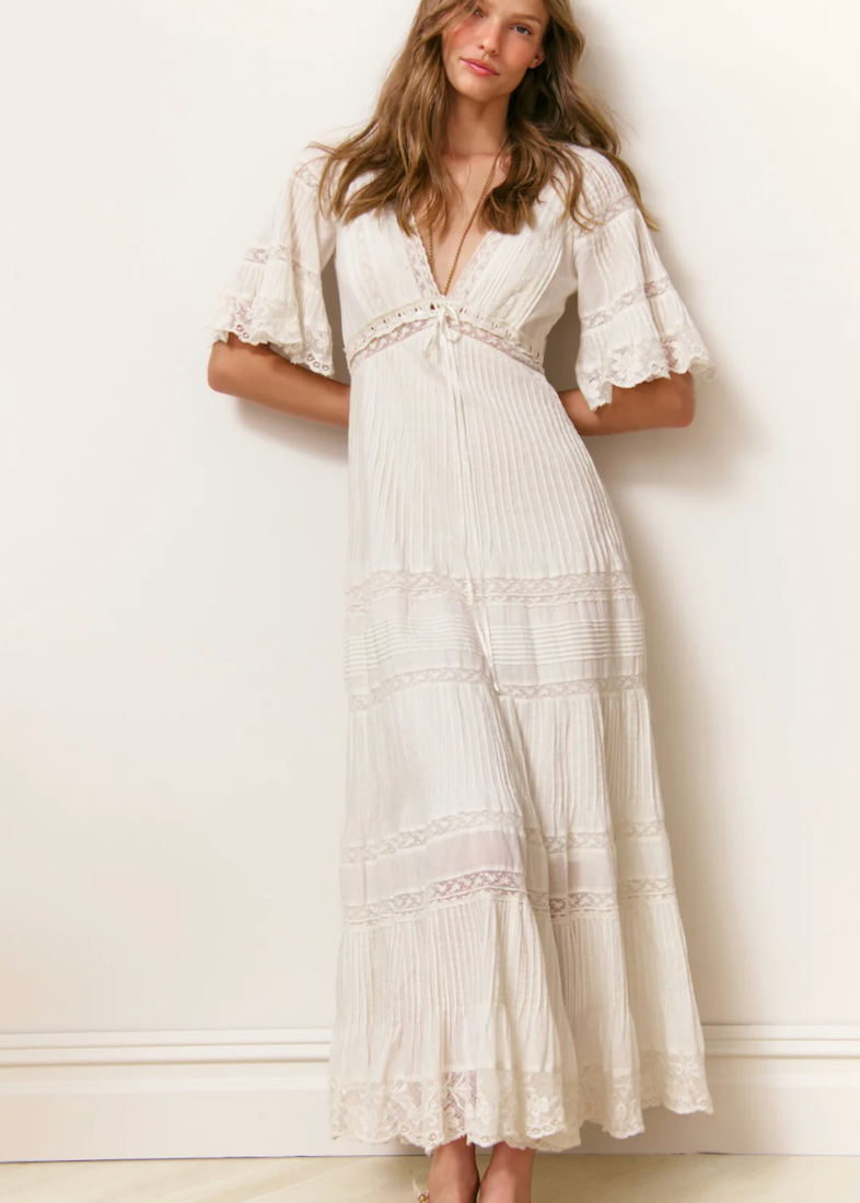Woman wearing a white dress with ruffled sleeves against a white background