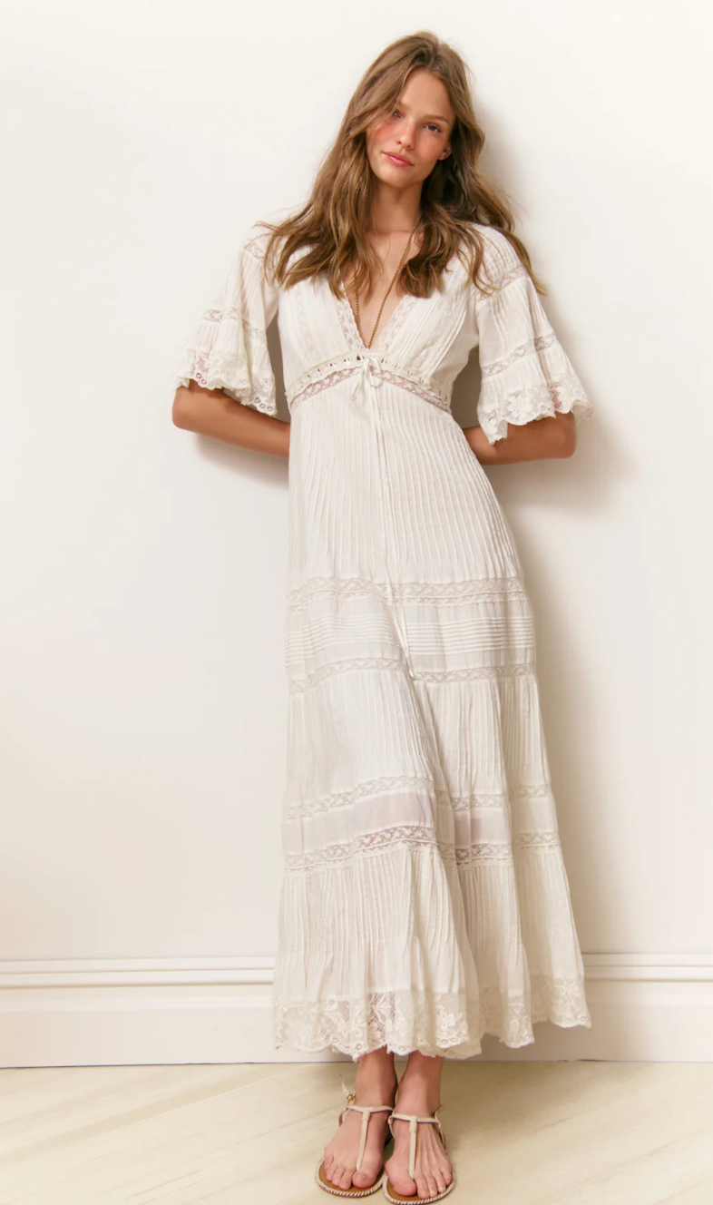 Woman wearing a white dress with ruffled sleeves against a white background