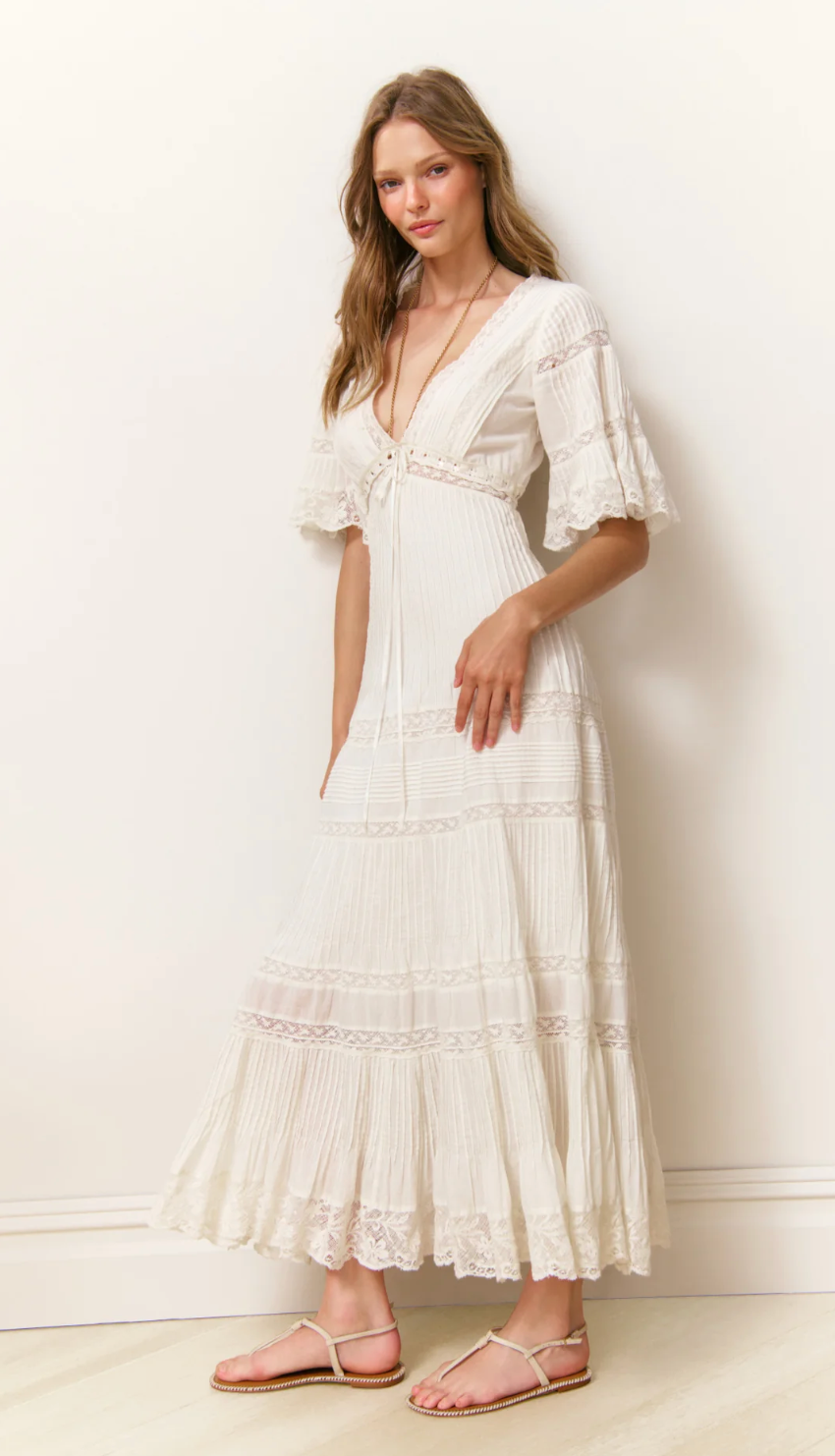 Woman wearing a white lace dress against a plain background