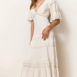 Woman wearing a white lace dress against a plain background