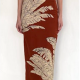 Woman wearing a rust-colored dress with leaf patterns on a white background