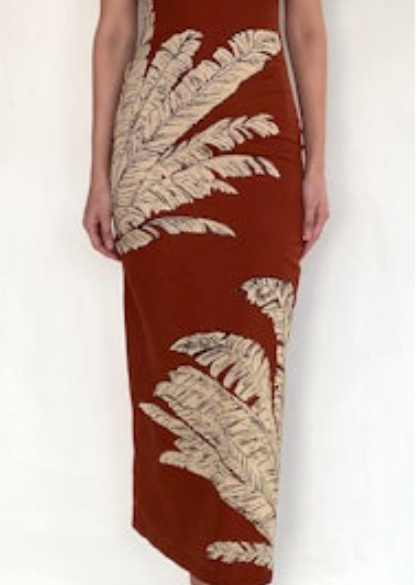 Woman wearing a rust-colored dress with leaf patterns on a white background