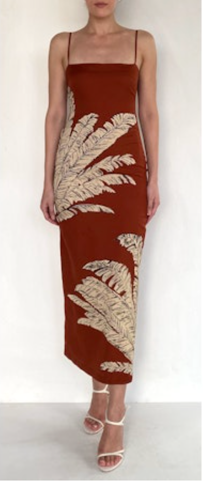 Woman wearing a rust-colored dress with leaf patterns on a white background