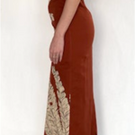 Woman wearing a rust-colored dress with gold embroidery on a white background