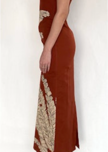 Woman wearing a rust-colored dress with gold embroidery on a white background