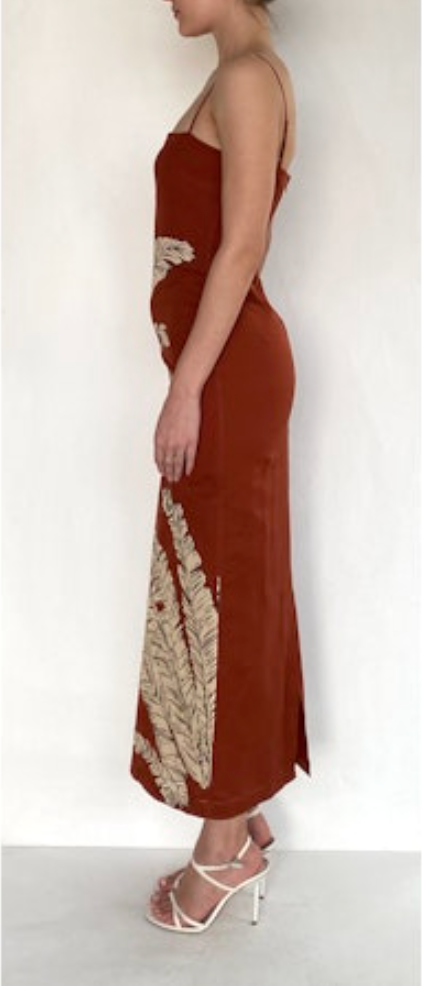 Woman wearing a rust-colored dress with gold embroidery on a white background