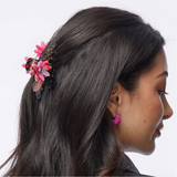 Woman with multi color floral hair accessory and earrings on a white background