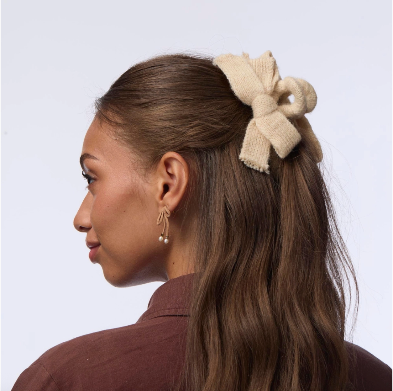 Woman with a beige hair bow in her hair against a light background