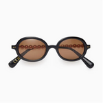 Black rounded sunglasses with brown lenses and stacked pearls as a temple-arm on a white background