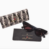 Black cat eye sunglasses with a patterned case and branded pouch on a white background