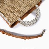 Straw handbag with pearl strap on a white background