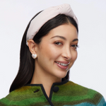 Woman wearing a pink headband and green sweater with a white background
