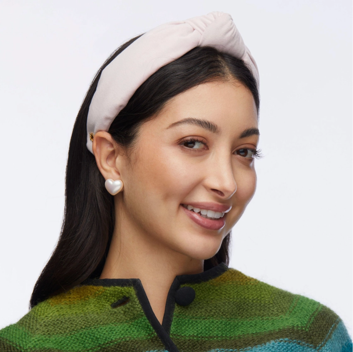 Woman wearing a pink headband and green sweater with a white background