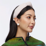 Woman wearing a light headband and green patterned sweater on a plain background
